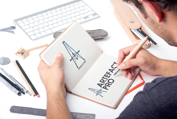 Hombre con cuaderno en la mano izquierda y bolígrafo en la mano derecha enseñando un logo de empresa de productos de tensegridad