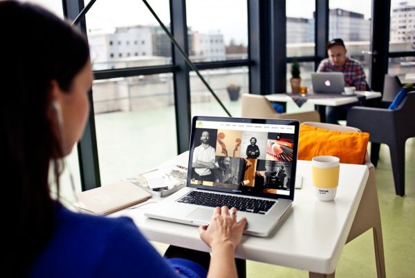 Mujer en coworking observando ordenador con página web de productora musical