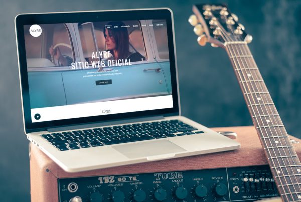 Ordenador sobre caja musical, y junto a una guitarra enseñando el sitio web