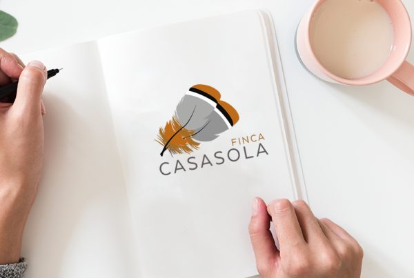 Folio en blanco, con logo de empresa y con unas manos dibujando el logo junto a una taza de leche