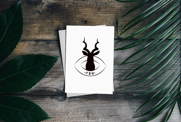 Folios blancos sobre mesa de madera con ambientación de plantas y logo de empresa